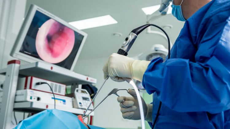 Arzt leuchtet bei einer Operation in die Nase des Patienten