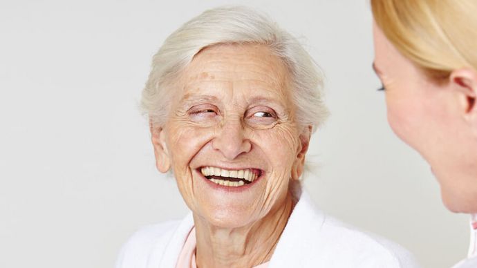 Anerkennung der Patient*innen Seniorin lacht weiblicher Pflegekraft an