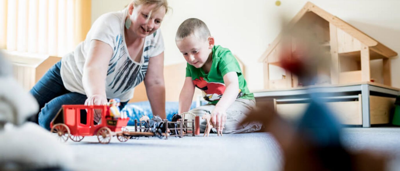 Therapeutin und Junge spielen mit Playmobil