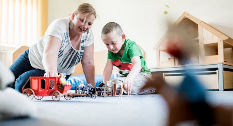 Therapeutin und Junge spielen mit Playmobil