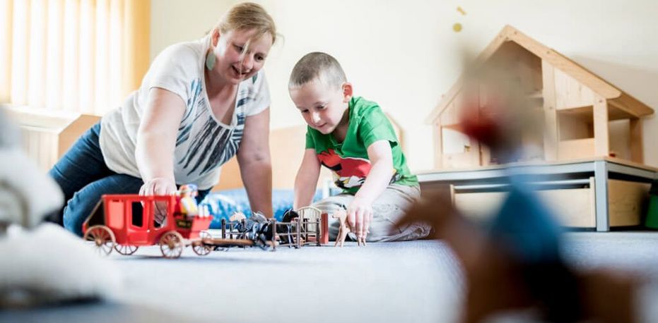 Therapeutin und Junge spielen mit Playmobil