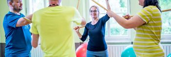 Patientinnen in der Akutpsychosomatik trainieren in der Bewegungstherapie mit Stöcken.