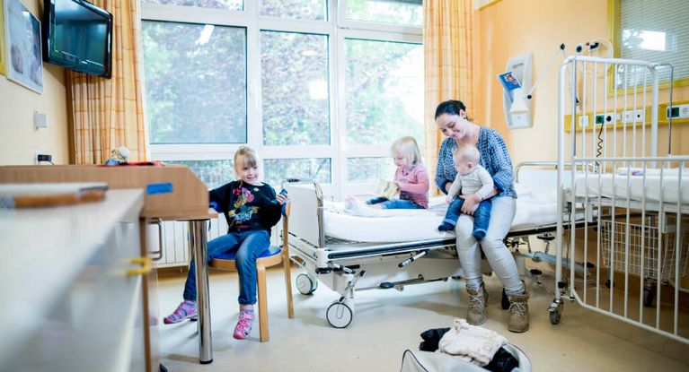 Aufenthalt im Zimmer Eine junge Mutter bezieht mit ihren drei kleinen Kindern ein Zimmer im Krankenhaus