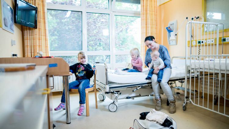 Eine junge Mutter bezieht mit ihren drei kleinen Kindern ein Zimmer im Krankenhaus