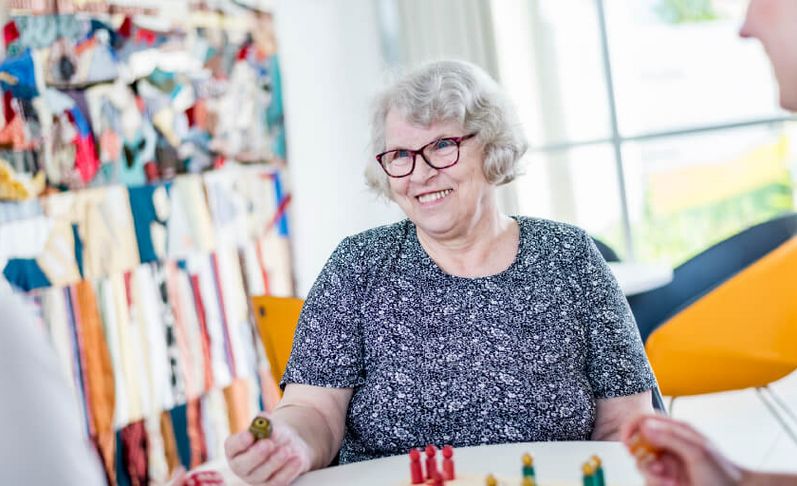 Zwei Therapeutinnen spielen mit einer alten Dame Mensch ärger Dich nicht.