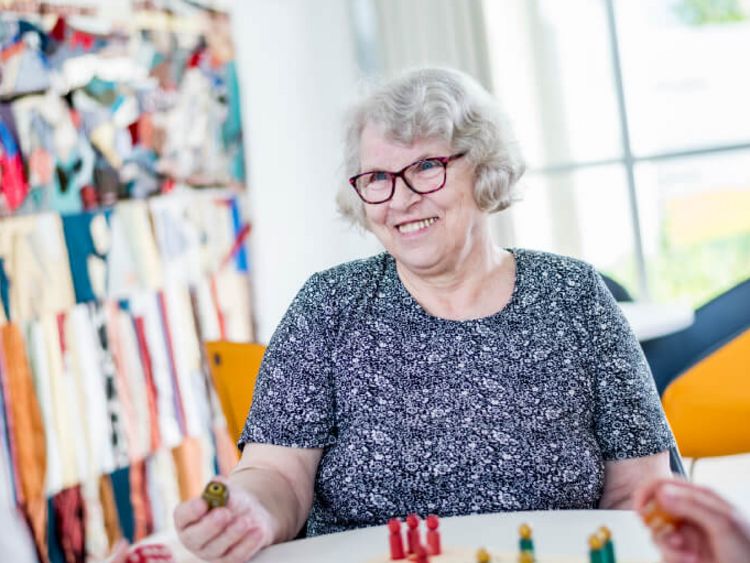 Zwei Therapeutinnen spielen mit einer alten Dame Mensch ärger Dich nicht.
