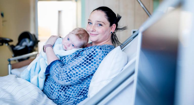 Eine junge Mutter hält ihr Neugeborenes auf dem Arm