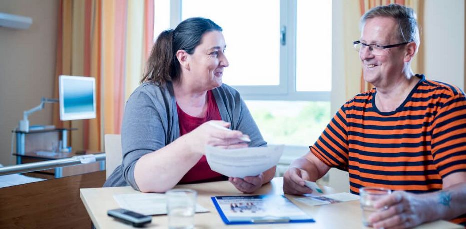 Eine Sozialarbeiterin berät einen Patienten zur Zeit nach dem Klinikaufenthalt