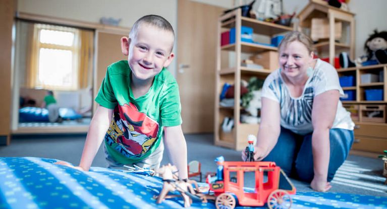 Junger Patient und Therapeutin spielen mit Playmobilpferden
