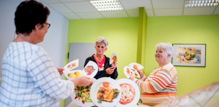 Therapeutin erklärt zwei Patientinnen, welche Lebensmittel gesund sind.