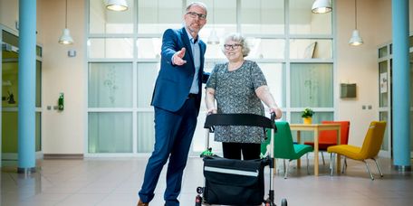 Arzt und Patientin Chefarzt führt einen Patienten mit Rollator durch die psychiatrische Klinik