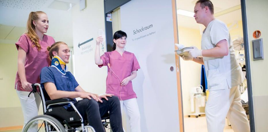 Pflegerinnen schieben einen jungen Patienten im Rollstuhl in den Schockraum